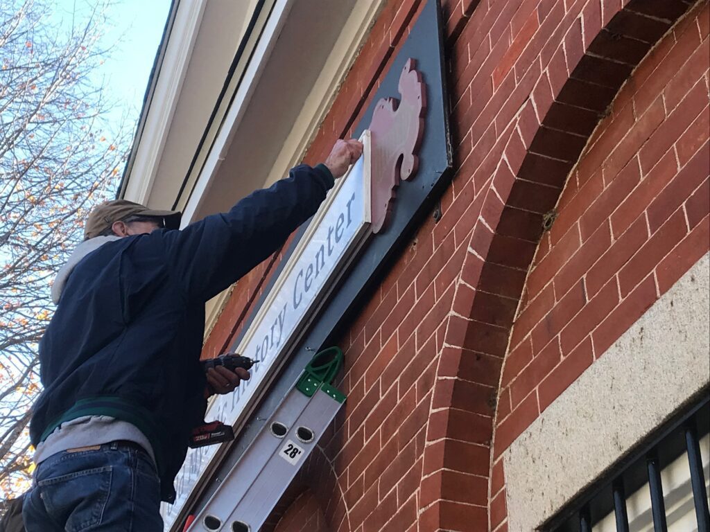 A Man Fixing an Old Mystic History Center Board