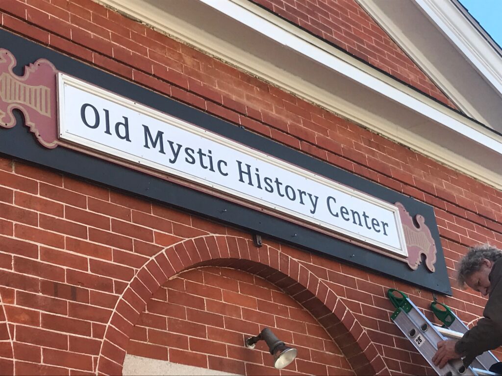 Old Mystic History Center Board Above a Building